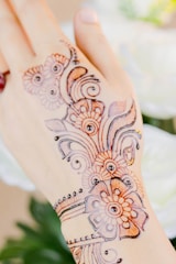 A close-up of intricate henna patterns adorning a bride's hands, glowing softly in natural light.