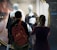 Two people stand in front of a store window display, observing mannequins dressed in lingerie. The storefront is branded 'MAISONLEJABY Paris'. One individual is taking a photo with a smartphone, while both focus on the display. The background features a large poster of a model.