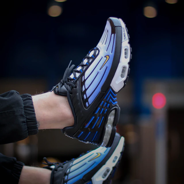 A person wearing blue and white Nike Air Max 95 sneakers