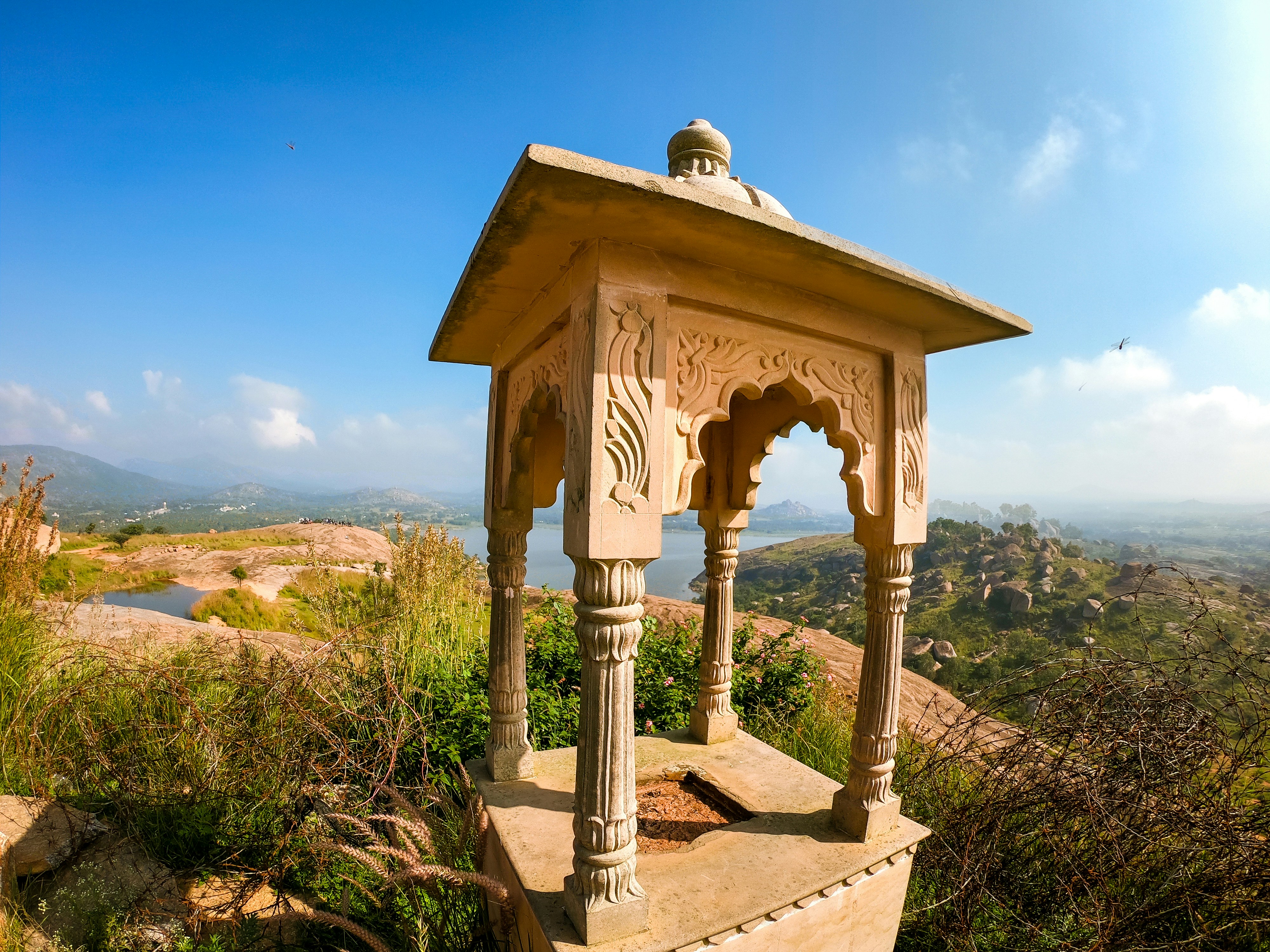 brown wooden gazebo viewing mountain and blue sea under blue and white sky during daytime