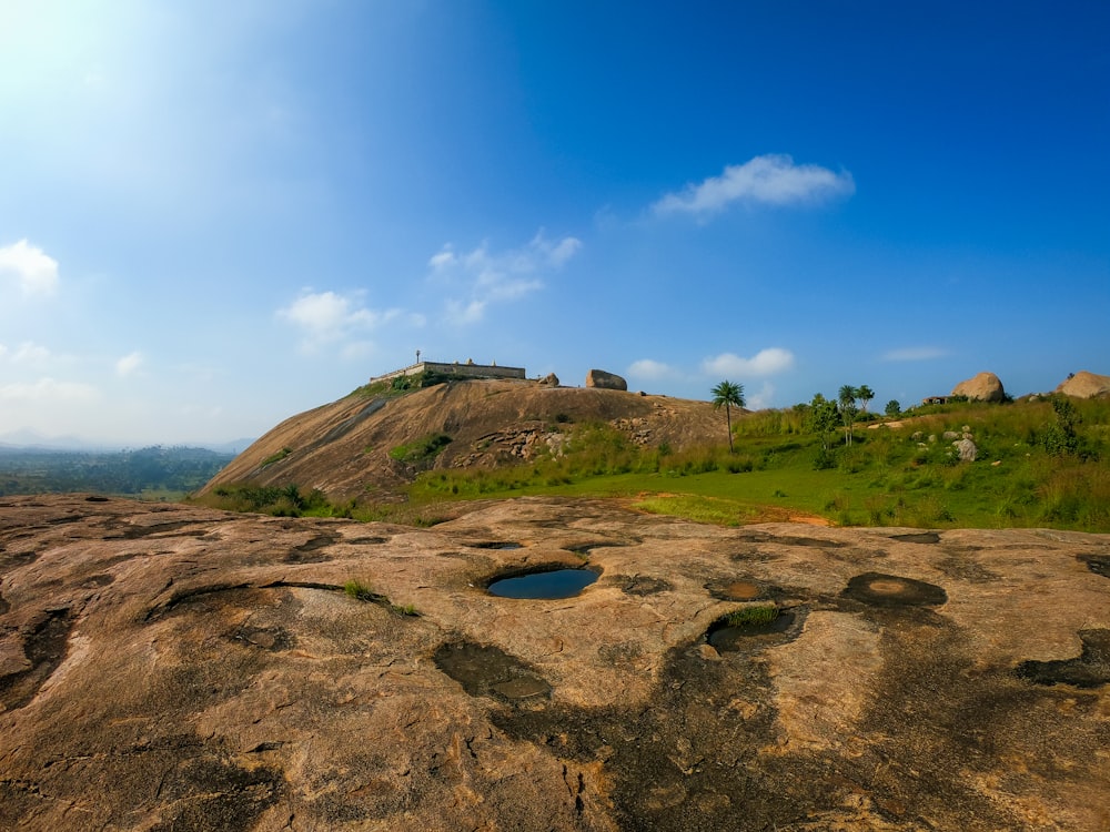 green field viewing mountain under blue and white sky during daytime