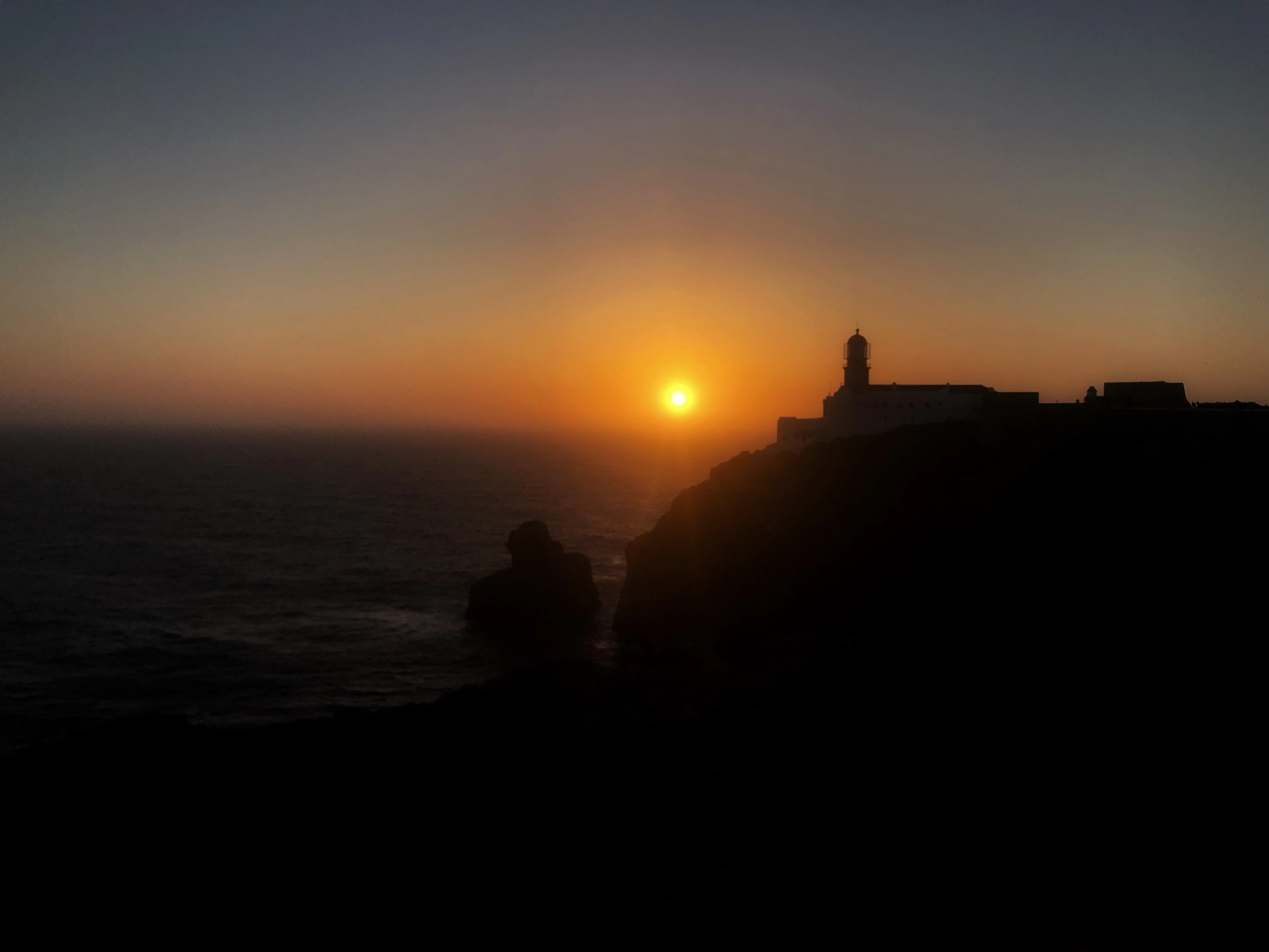 The lighthouse at Cabo de São Vicente silhouetted against a fiery sunset.