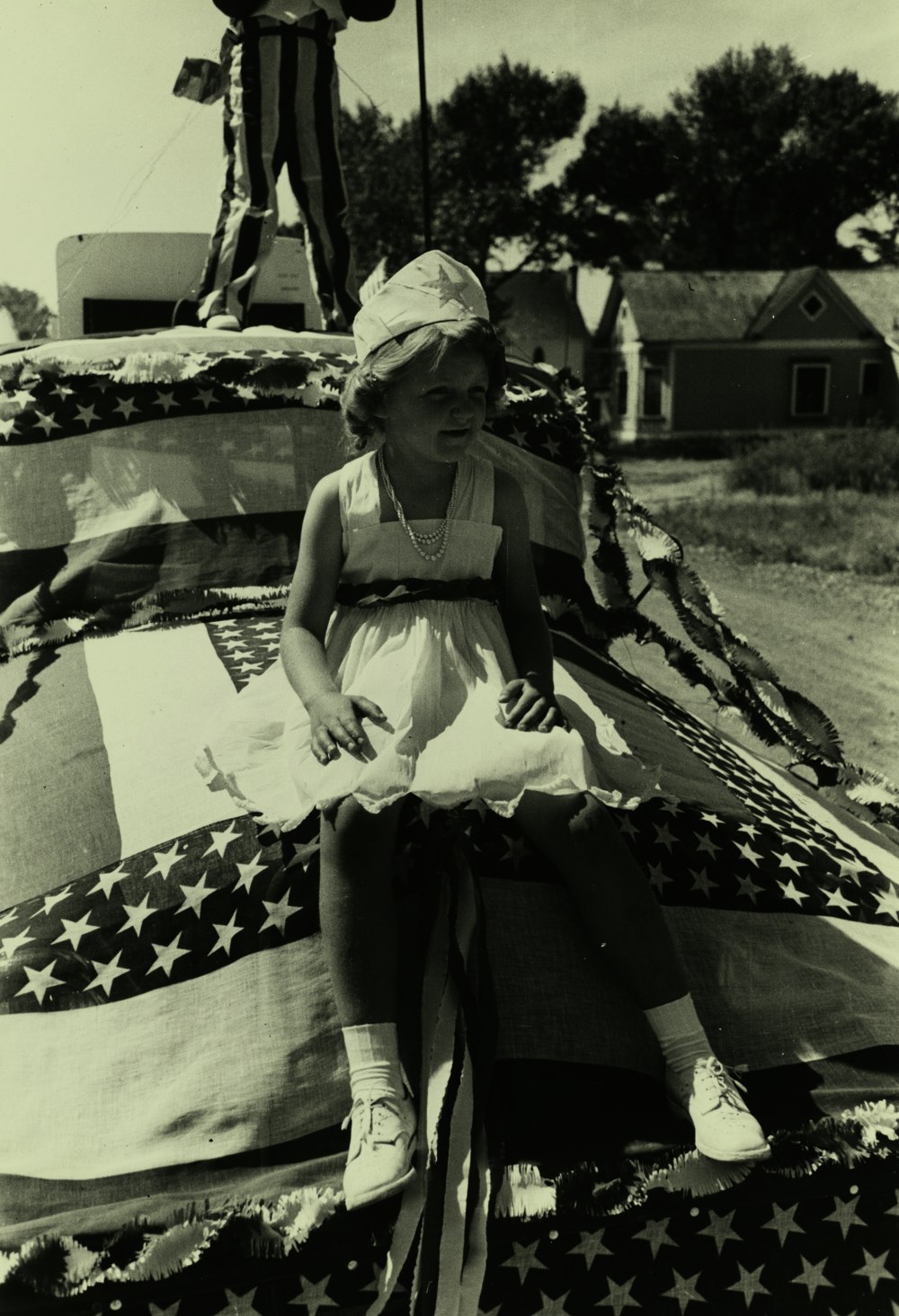 Graustufenfotografie eines Mädchens, das auf der Flagge sitzt