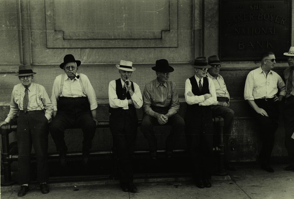 men leaning and sitting on metal railing