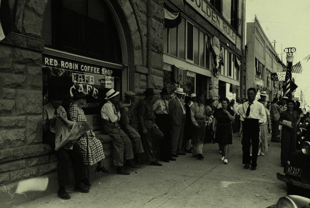 grayscale photography of people beside buildings during daytimne