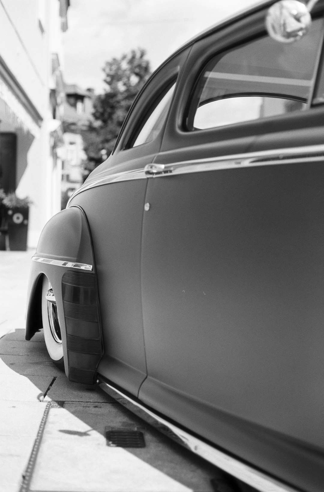 grayscale photo of car parked near building