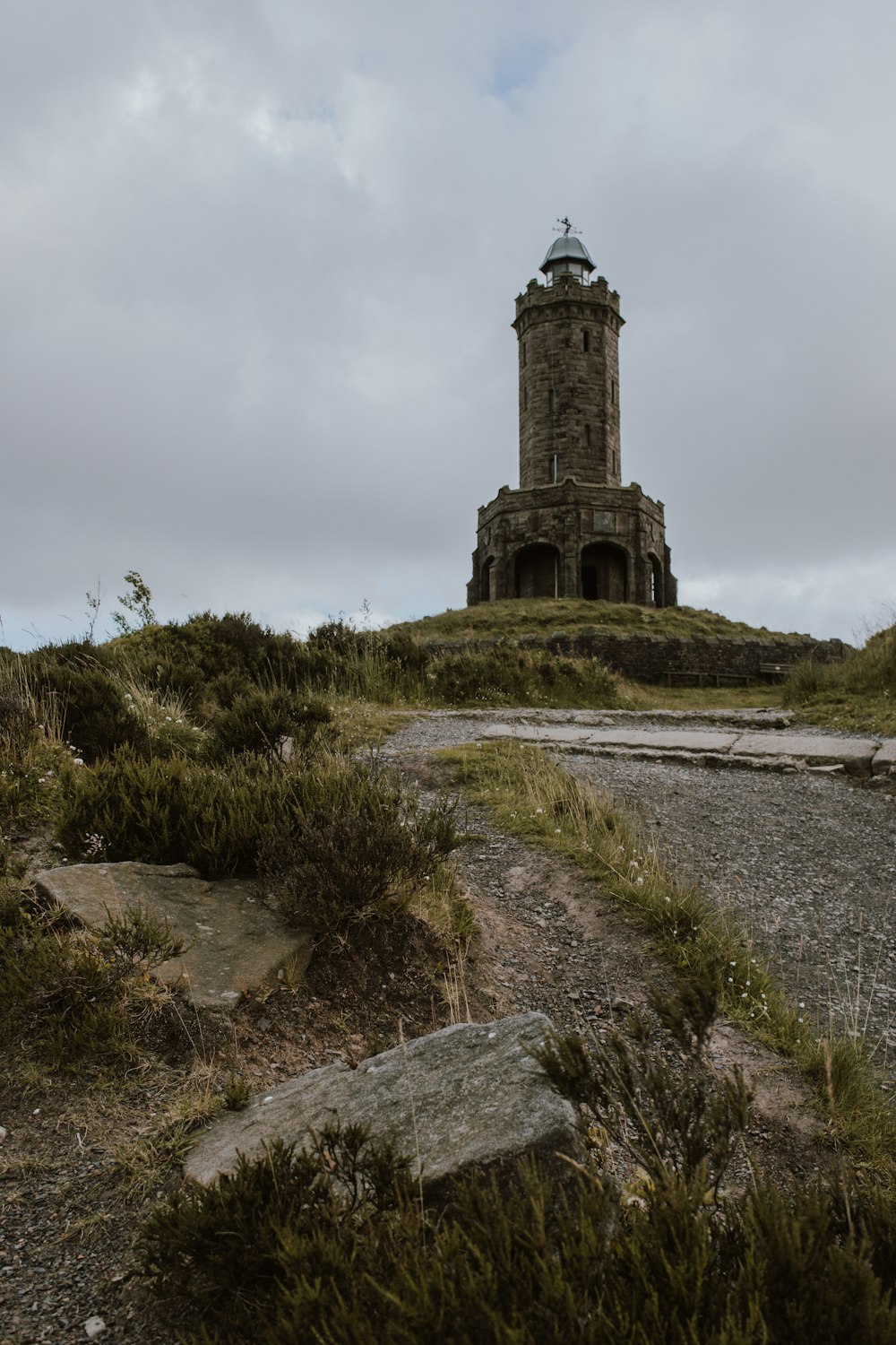 tower on grass field near rocky road during day