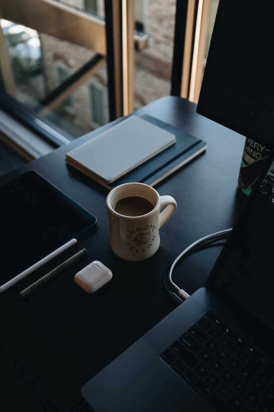 A person at a desk in the afternoon with a cup of coffee
