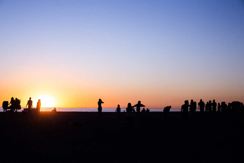 Silhouette de personnes près du plan d’eau pendant l’heure dorée