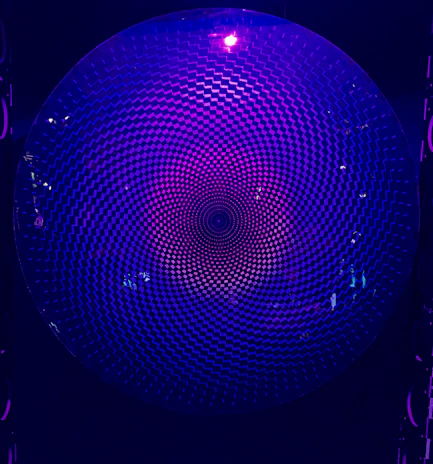 A glowing sacred geometry pattern softly illuminated in neon purple and gold against a deep charcoal background.