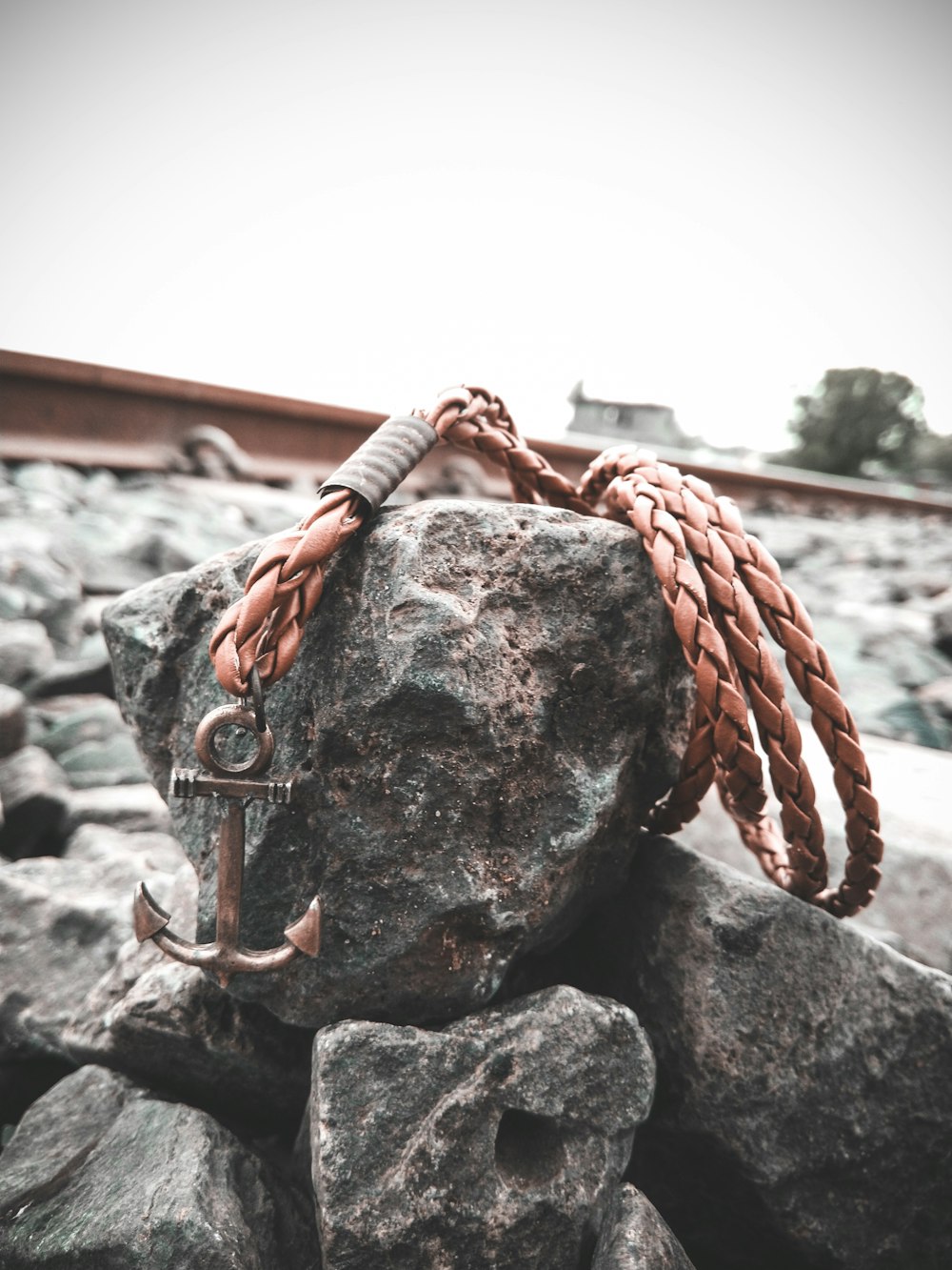 brass-colored anchor pendant on brown leather woven necklace