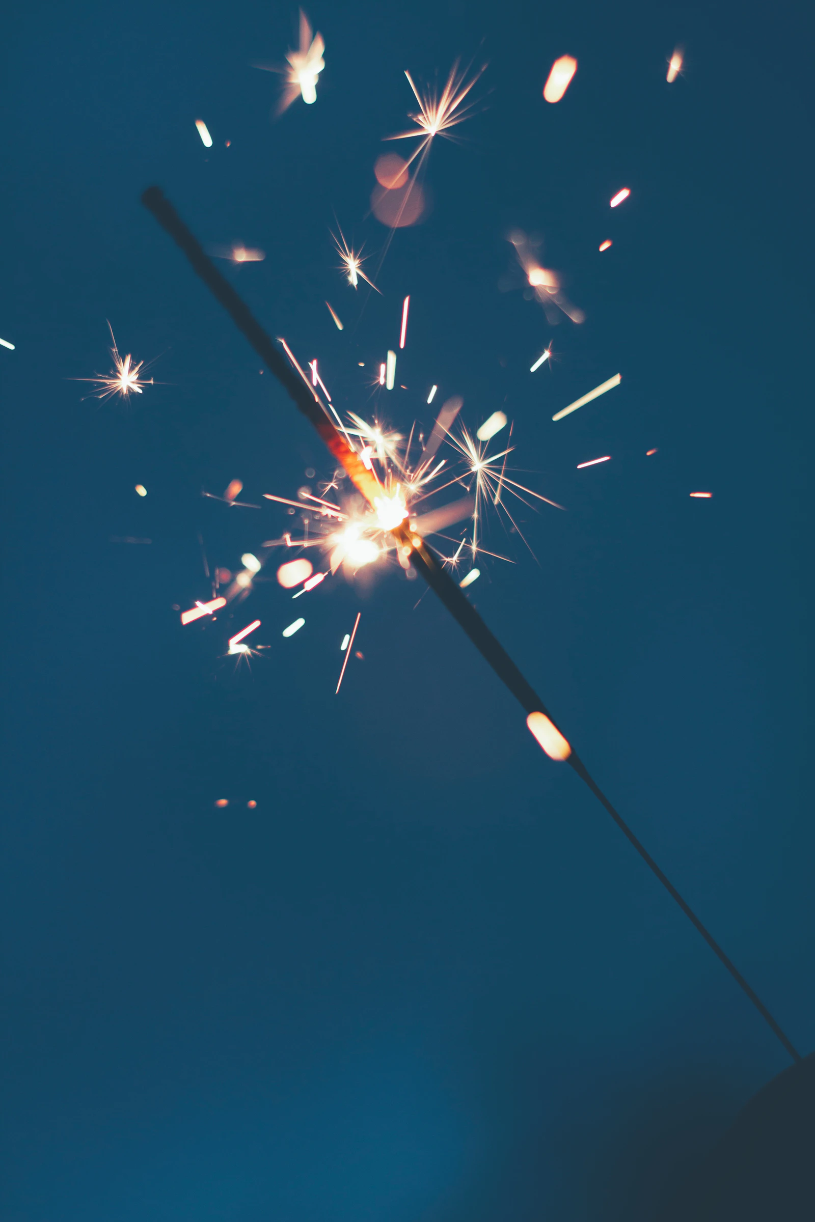 lit sparkler against a dusk sky