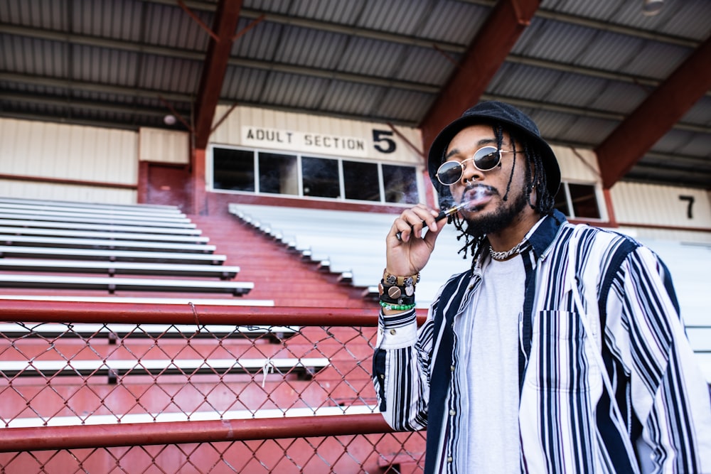 man wearing black and white striped zip-up jacket standing near bleachers