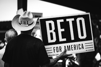 greyscale photography of person holding Beto for America signage