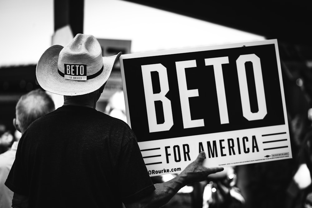 fotografía en escala de grises de una persona sosteniendo el letrero de Beto for America