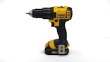 A compact cordless drill with a black and yellow design placed on a wooden workbench.