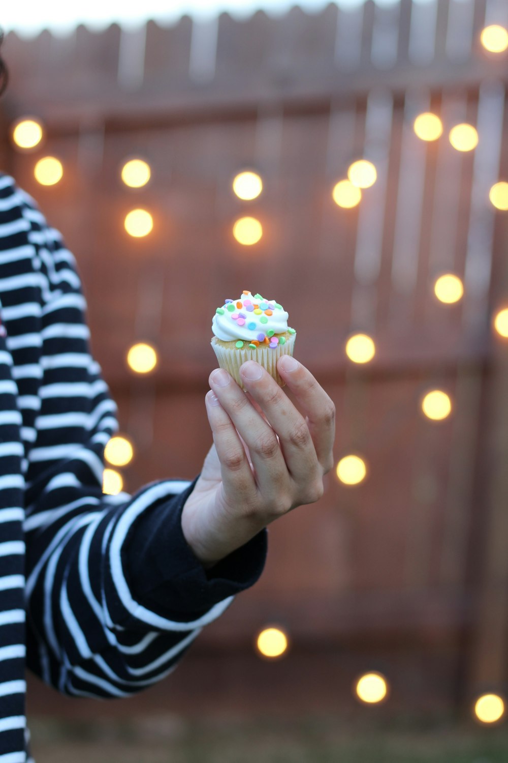 person holding multicolored cupcake