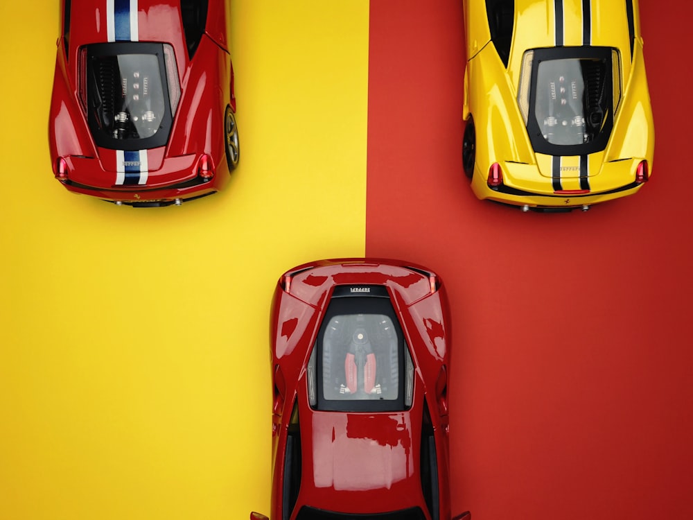 yellow and two red diecast sports car models on red and yellow background