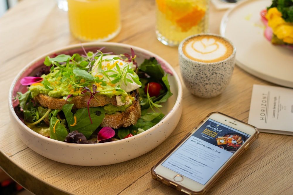 gold iPhone 7 beside vegetable salad on bowl