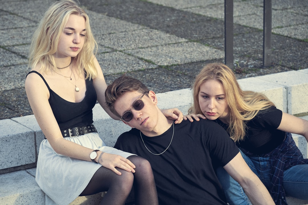 photo shoot of man sits between two women on staircase