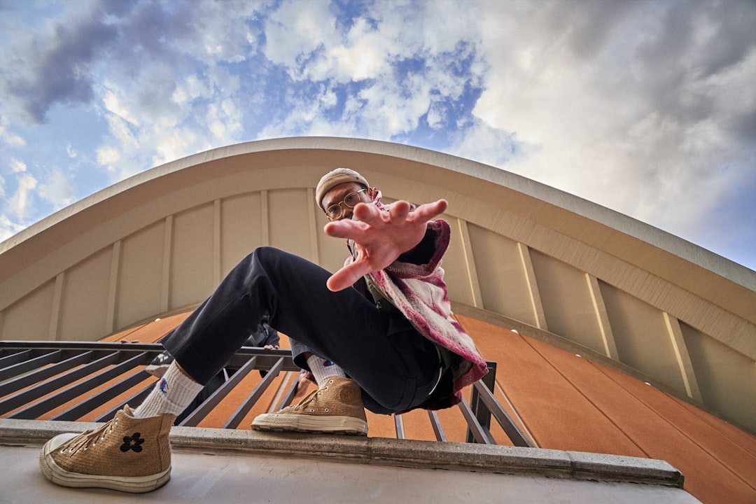 man hangs on handrail under cloudy sky