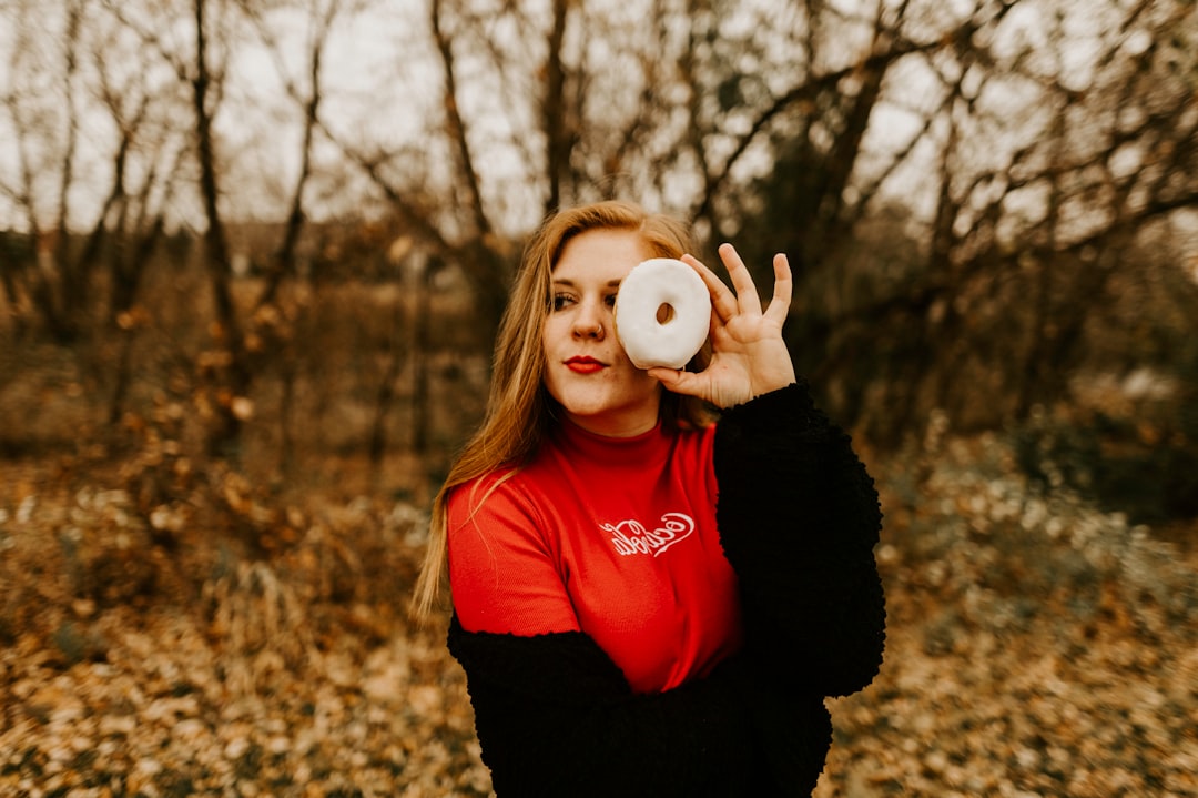 woman holds doughnut near her left eye