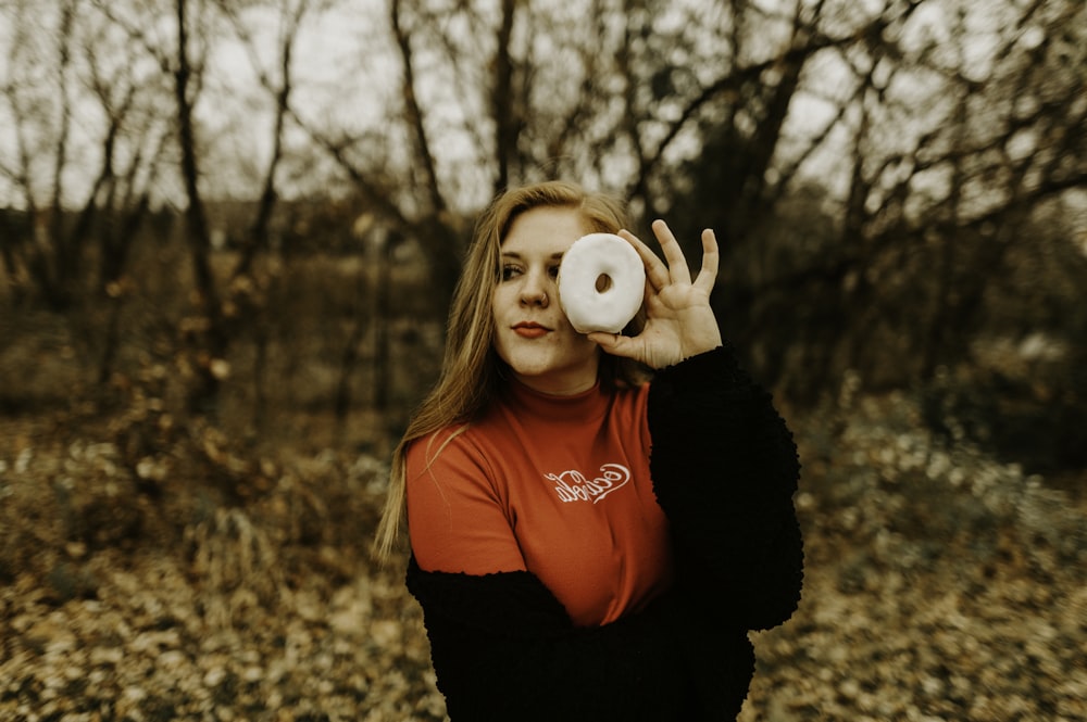 woman holds doughnut near her left eye