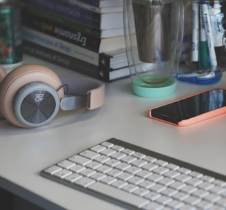 grey and white computer keyboard beside grey headphones