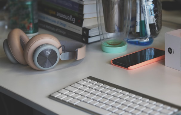 grey and white computer keyboard beside grey headphones