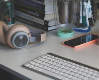 grey and white computer keyboard beside grey headphones