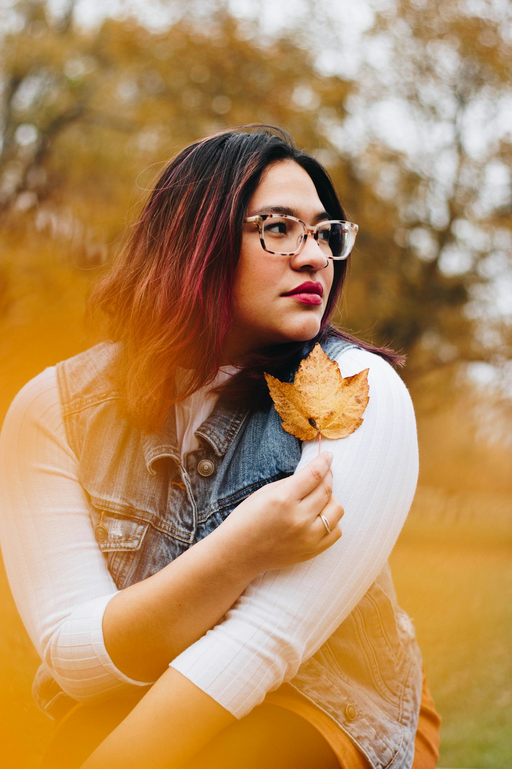 photo shoot of woman holds dried leaf near to her left shoulder