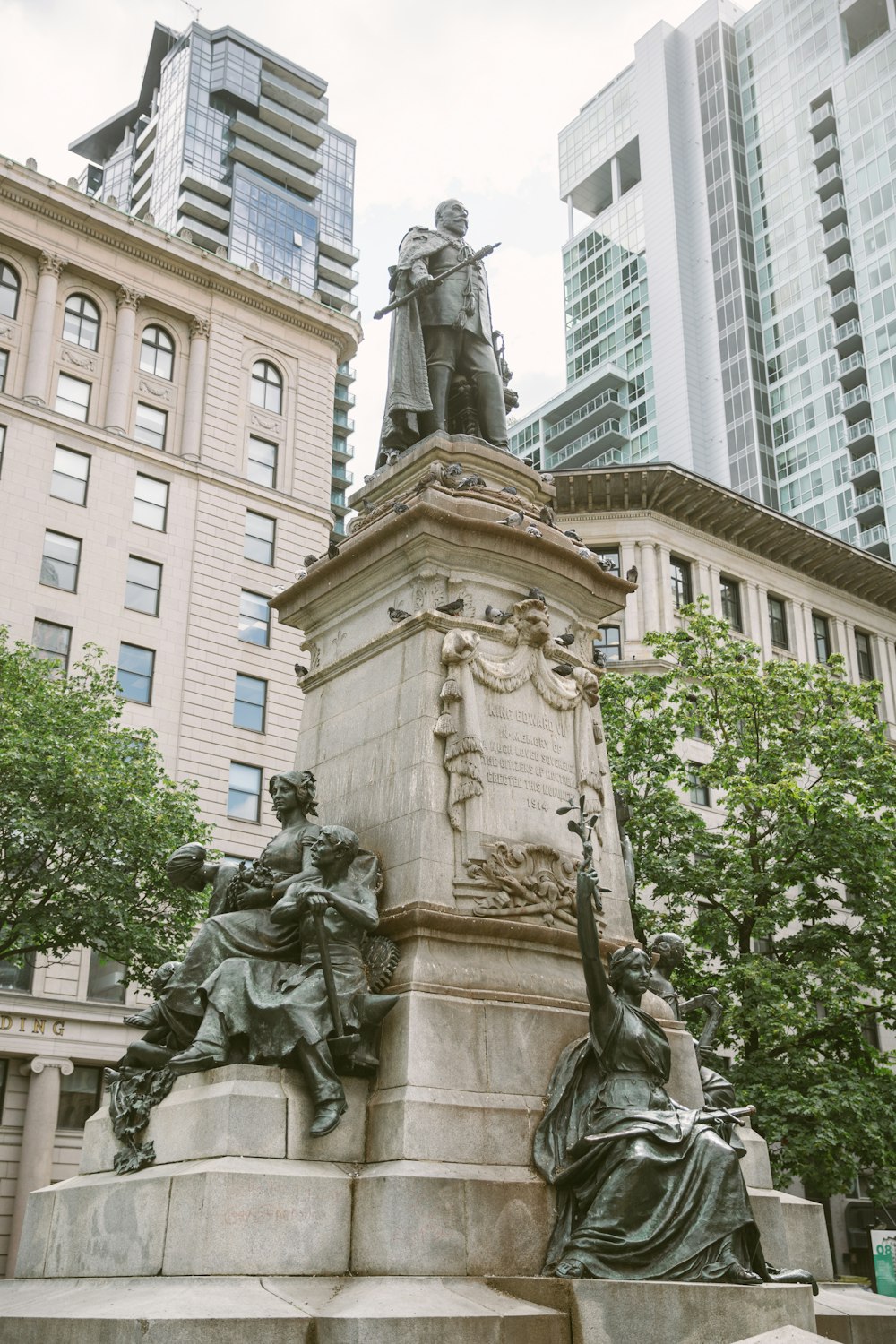 man holding sword statue near white high-rise building during daytime