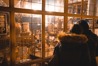 A cozy indoor scene with a couple trying on jackets in front of a mirror, laughing together.