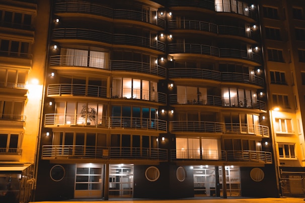 The modern facade of a 3 BHK apartment building at vvip namah with warm lighting at dusk.