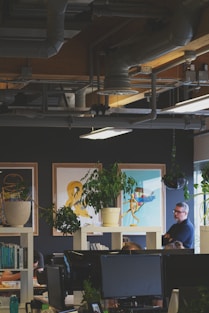 man sitting crossing hands beside plant