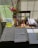 Close-up of office desk with books, paper, pens, and a laptop in natural light.