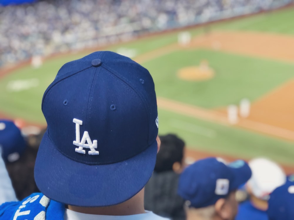 selective focus photography of person wearing LA Dodgers cap looking at field