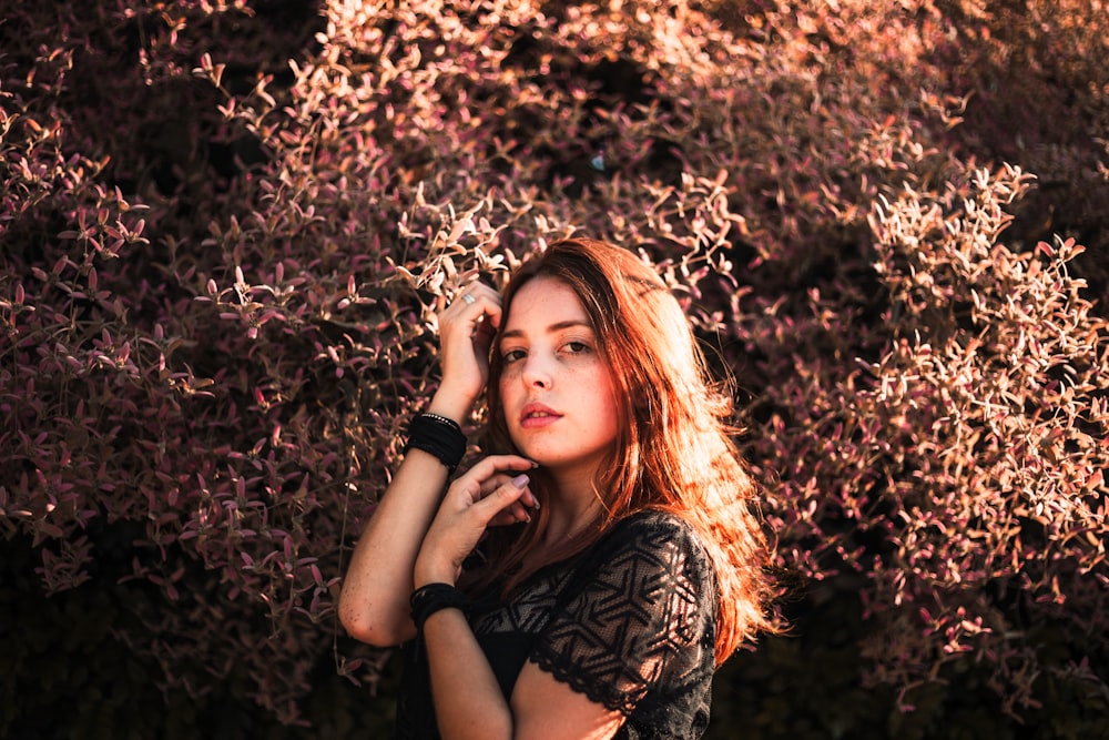 selective focus photography of woman standing beside green plant during daytime