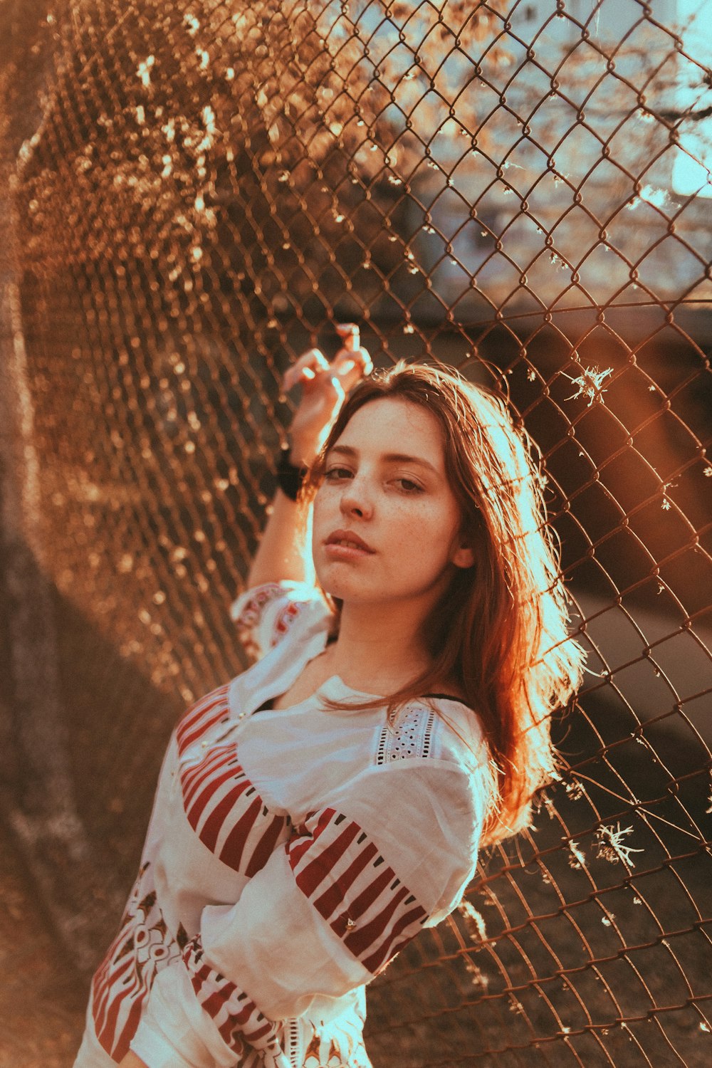 selective focus photography of woman standing beside chain link fence during daytime