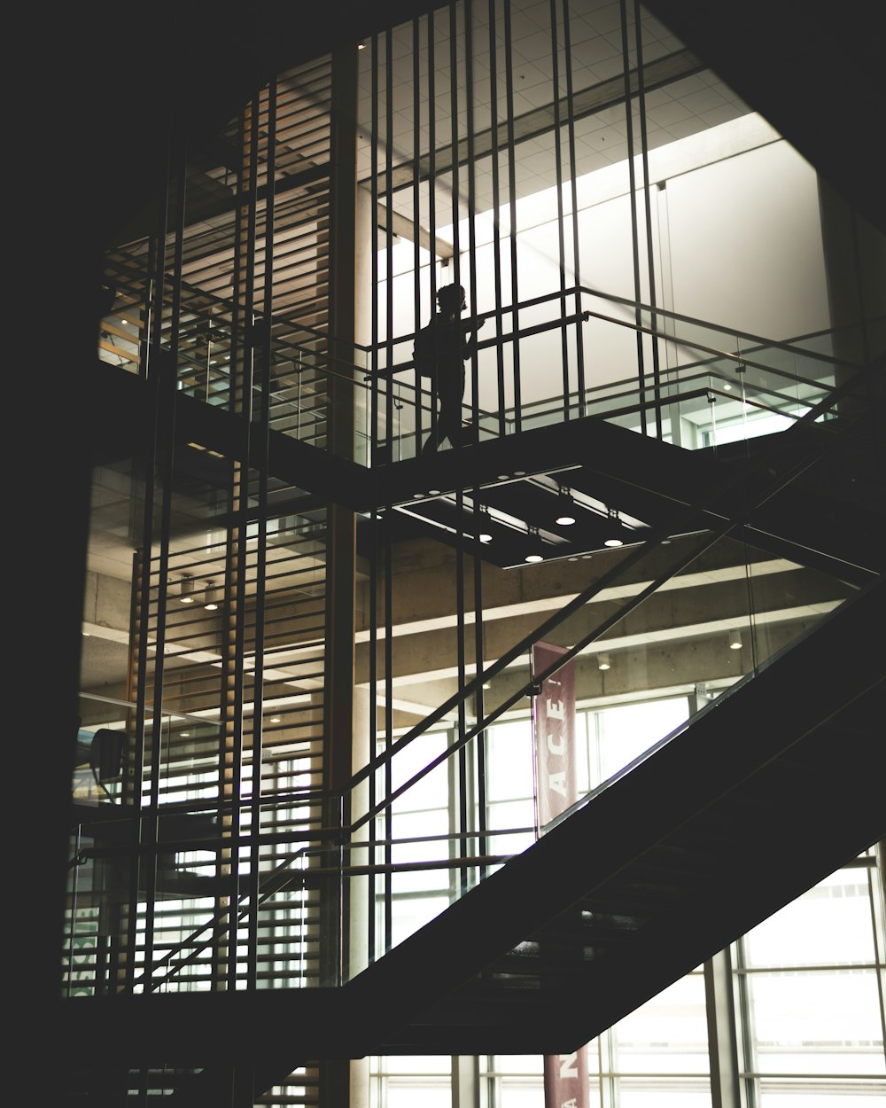 silhouette of person walking down the stairs inside building