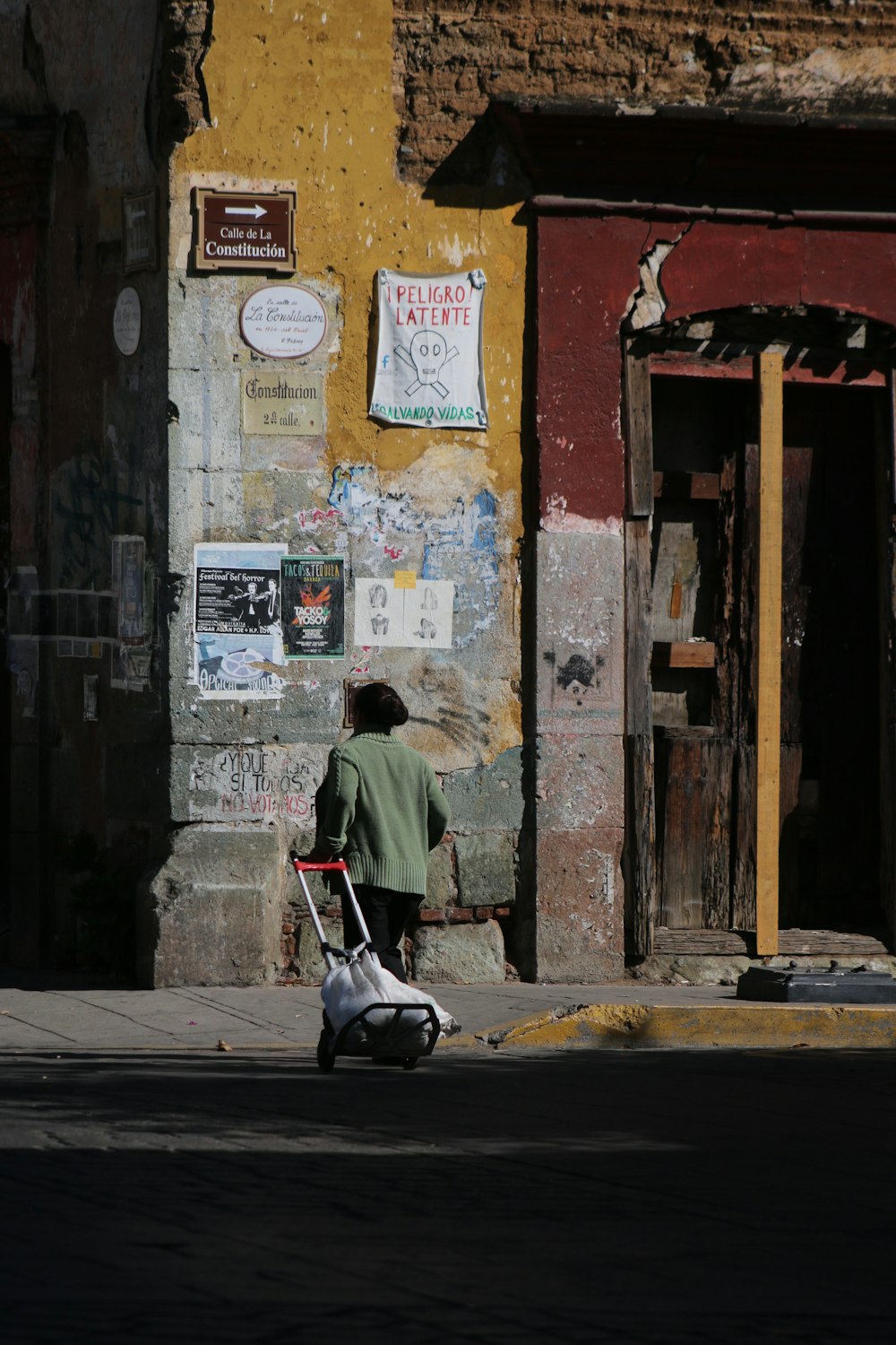 photography of girl pulling a trolley toward building during daytime