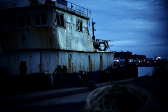 A ruined dock at twilight with shadowy figures hiding behind crates.