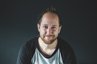 Man with a man bun smiling in front of a green wall