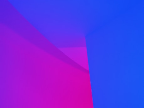 A minimalist abstract scene composed of intersecting planes and gradients with predominant colors blending smoothly from vibrant pink to deep blue, creating a gradient effect. The clean lines and smooth color transitions evoke a sense of modern design.