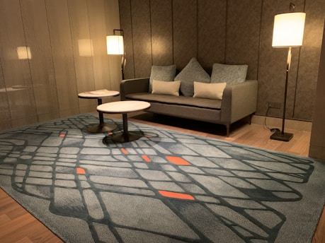 two round white tables beside sofa between floor lamps