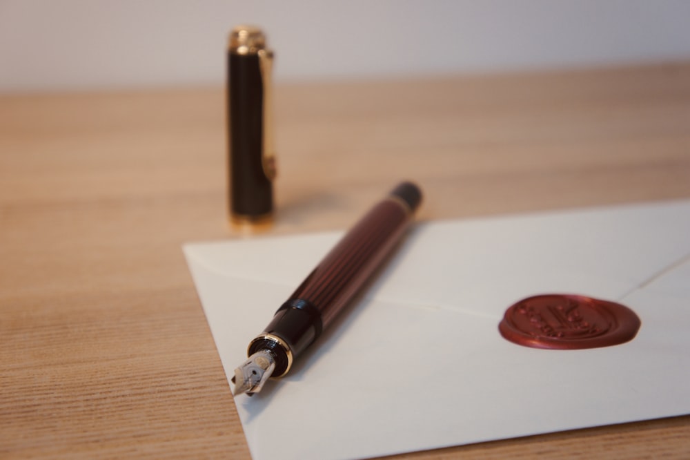 selective focus photography of red fountain pen on white letter with red stamp