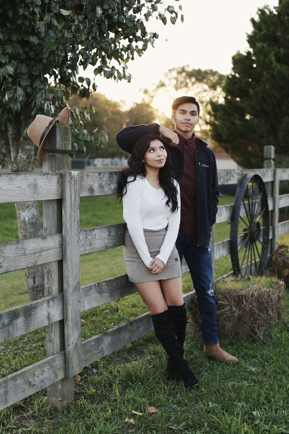 man and woman leaning against a wooden fence