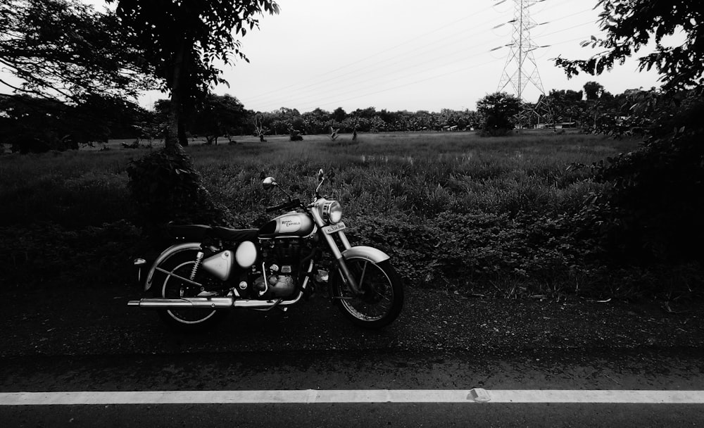grayscale photography of motorcycle parked beside road