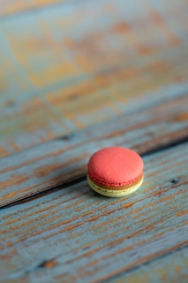 Close-up of a perfectly crafted macaron with delicate pastel colors on a rustic wooden table.