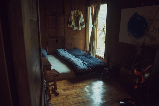 Sunlit shared room with comfortable beds and rustic wooden decor.